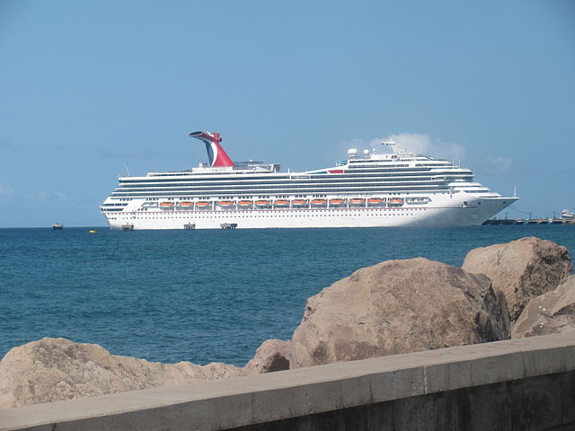 Carnival Cruise Lines Carnival Valor at Port. White cruise near dock and rocks.