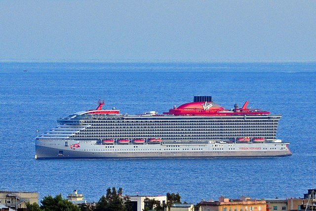 Virgin Voyages Scarlet Lady. Red Cruise ship along cube style houses.