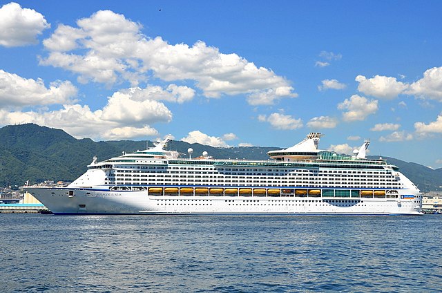 Royal Caribbean Voyager of the Seas at the Port of Kobe. White cruiseship docked along forest covered mountains.