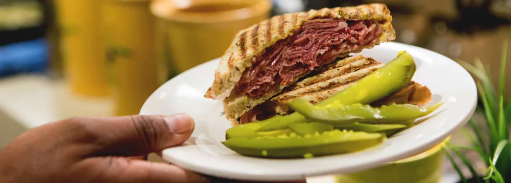 Closeup of a grilled Reuben and pickles. Get food at midnight at the Carnival Deli instead of a midnight buffet on Carnival Cruise.