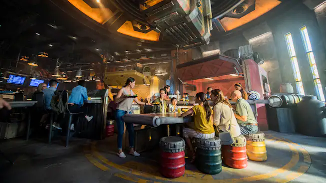Indoor Seating for Docking Bay 7 Food and Cargo in Hollywood Studios. Star Wars themed restaurant with barrels for seating, parts of spaceships scattered about, futuristic menu boards, etc.