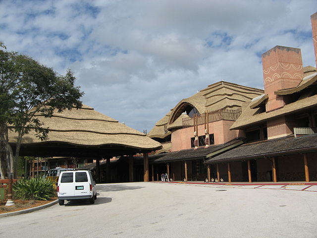 Entrance to Animal Kingdom Lodge. Beige Building with parking loop and White Van outside, trees and plants,
