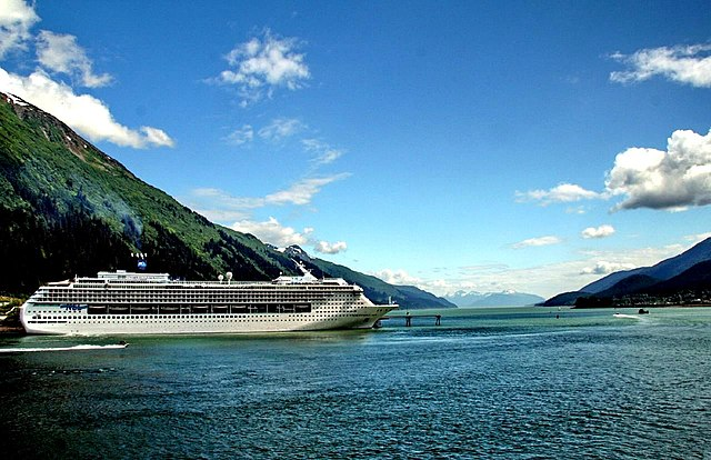 Cruise Ship sailing through Alaska. Plant covered mountains in the background.